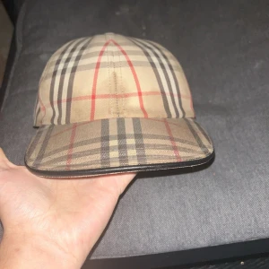 Burberry keps - Säljer en Sällsynt burberry keps då jag byt stil helt och inte använder den. Den har en fläck på framsidan som man kan se som går bort hos kemtvätten. Kepsen är storlek M bortsätt från fläcken är det inga konstigheter på den. Box och kvitto samt äktehetsbevis finns. Pris kan diskuteras vid snabb affär. Den är köpt hos en äkta företag som säljer märkes kläder och dom konstrollersr att kläderna är äkta innan dom säljs!