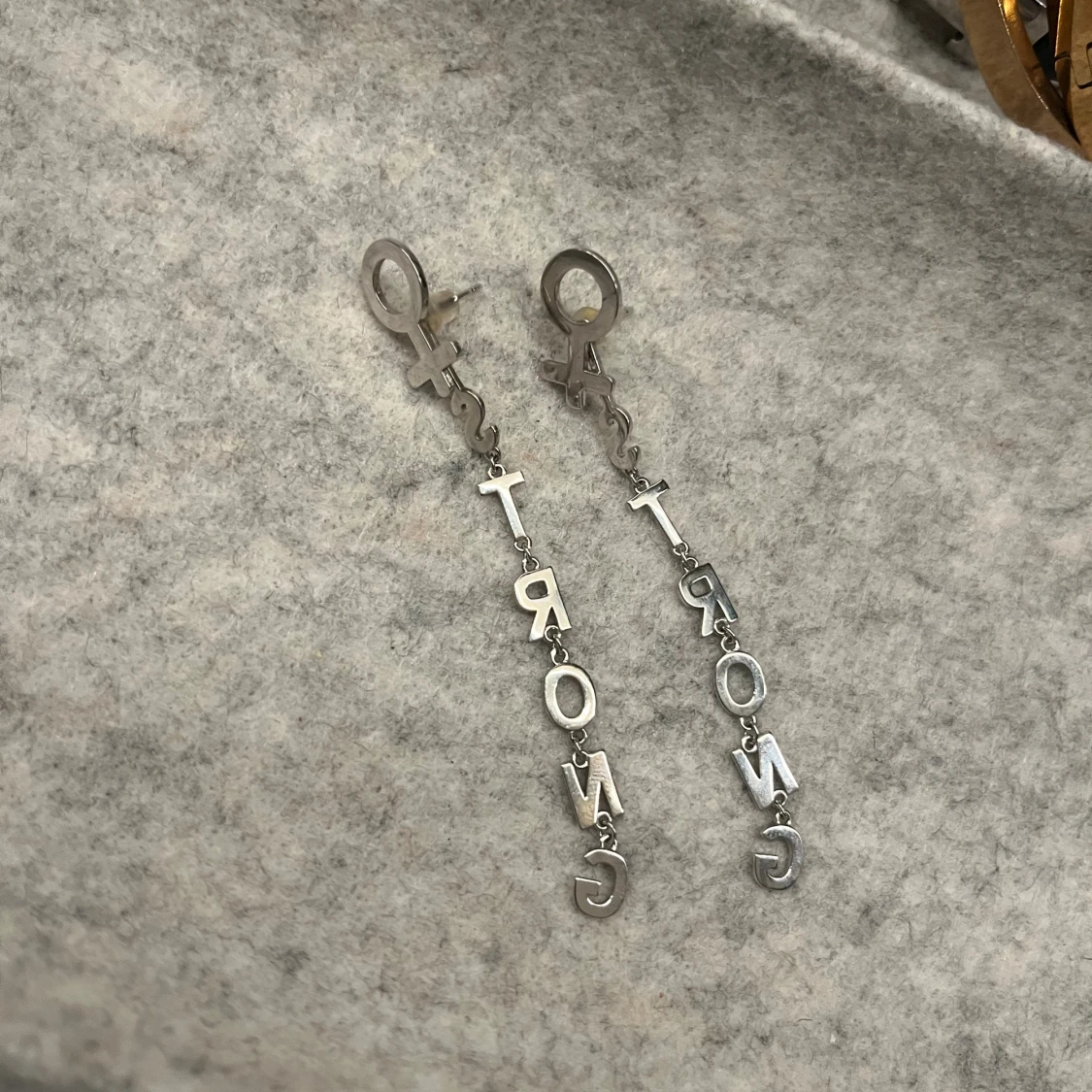 Silvriga örhängen med texten STRONG ifrån Ioaku