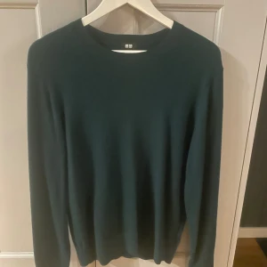 Mörkgrön kashmirtröja från Uniqlo - Säljer en stilren mörkgrön tröja från Uniqlo i 100% kashmir. Tröjan har rund halsringning och långa ärmar, perfekt för dig som gillar en klassisk och mjuk look. Passar lika bra till jeans som till kostymbyxor.