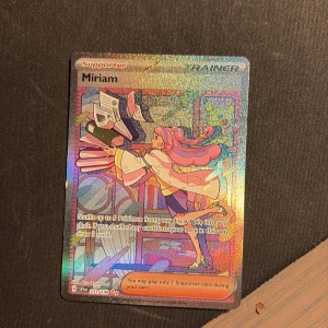Miriam (Pokémon Trainer Card) - Cool och glittrig Pokémonkort med karaktären Miriam! Perfekt för dig som samlar eller spelar Pokémon TCG. Korten är färgglada och har snygg anime-inspirerad design som gör dem extra populära bland unga samlare.
