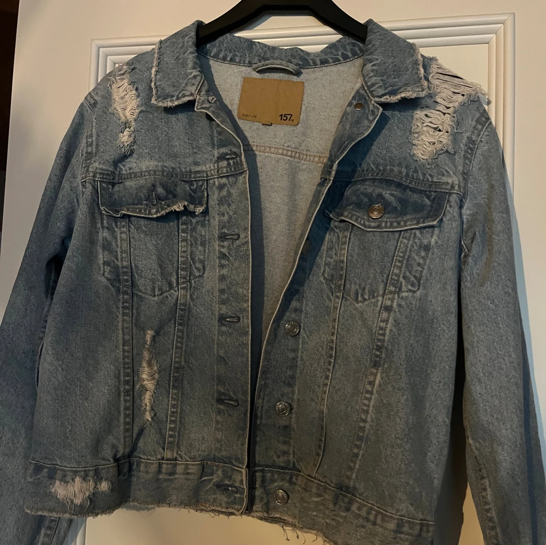 Ljusblå jeansjacka med slitningar