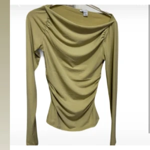 Ljusgrön långärmad topp New Yorker - Långärmad topp med draperad front och lätt rynkade detaljer vid axlarna. Toppen har en smickrande och figurnära passform. Perfekt för dig som gillar trendiga och stilrena plagg.
