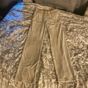 Juicy Conture byxor - Ett par beige juicy Conture byxor. Dom är i storlek XS. Allting är i bra skick förutom att det är en silvrig metall sak som ska sitta på snören som ni kan se på bilden. Det finns också en liten liten fläck som ni kan se på sista bilden men den är inte så synlig men går säkert bort i tvätten om man skrubbar. Annars fin skick köpta för 1000kr!❤️