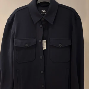 Mörkblå overshirt från Zara - Snygg mörkblå overshirt från Zara med klassisk krage och två stora bröstfickor med knappar. Rak passform och långa ärmar, tillverkad i ett tjockare bomullsmaterial. 