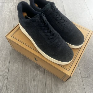 Mörkblå Ralph Lauren skor - Snygga mörkblå sneakers från Polo Ralph Lauren i mjuk mocka med vit platt sula och diskret logga på sidan. Användes aldrig för dom var för stora så nyskick.