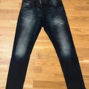 Svarta jeans med tvättad look - Säljer ett par svarta jeans med snyggt tvättad effekt och lätt slitna detaljer. Jeansen har klassisk femficksdesign och rak passform som sitter bekvämt. Perfekta för dig som gillar en avslappnad och stilren vibe.