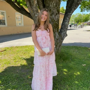 Balklänning/långklänning - Säljer min superfina balklänning som jag var så nöjd med! Klänningen har axelbandslös design med ett band framtill som man kan knyta på det sätt man föredrar. Jag är 165 och den gick ner så att fötterna inte syntes.