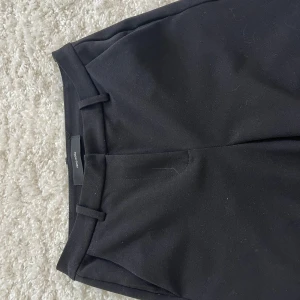 Svarta kostymbyxor - Svarta kostymbyxor med klassisk rak passform. Byxorna har en stilren design och är perfekta för en clean och snygg look. Materialet känns mjukt och följsamt, vilket gör dem bekväma att bära hela dagen. Köpta för ca 400