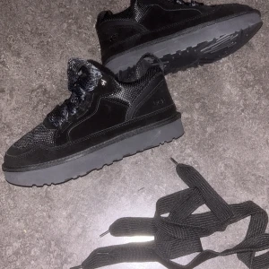 Svarta sneakers från UGG med plattform,skosnören kommer med - Säljer ett par svarta sneakers från UGG med plattformssula. Skorna har en kombination av mocka och mesh, samt snörning och rund tå. Snyggt och stilrent designade, perfekta för dig som gillar chunky sneakers med extra höjd.