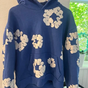 Denim tears hoodie - Säljer denna denim tears hoodien i exklusiva färgen blå. Väldigt bra skick är dock liten i storlek så det står L i tröjan men passar medium. Skit snygg och passar allt! Obs denna färg är svårare och få tag i och dyrare än andra färger.