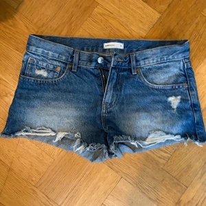 Blå jeansshorts med slitningar - Säljer ett par blå jeansshorts från Gina i storlek 36. De har snygga slitningar. De är förstora för mig så endast använda några få gånger 