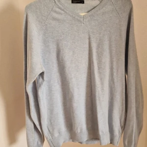 Ljusblå v-ringad tröja Cedarwood - En stilren ljusblå v-ringad tröja från Cedarwood State. Tröjan har lång ärm och ribbade muddar vid ärmslut och nederkant. Perfekt för lager-på-lager och passar till både jeans och chinos.