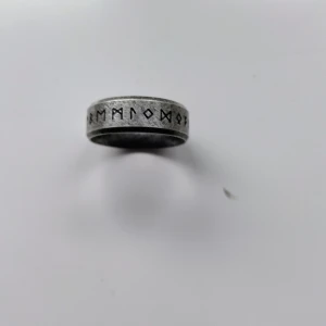 Bred silverfärgad ring med runor - Coo 8 mml bred  ring i silverfärg med ingraverade runor runt hela bandet. Ringen har en matt finish och ger en rå, nordisk vibe. Perfekt för dig som gillar unika detaljer och vill sticka ut med din stil.