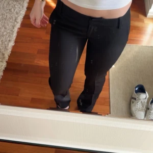 Svarta kostymbyxor med rak passform - Säljer ett par svarta kostymbyxor med klassisk rak passform och midja. Byxorna har hällor för bälte och stängs med dragkedja och knapp. Perfekta för en clean och stilren look.