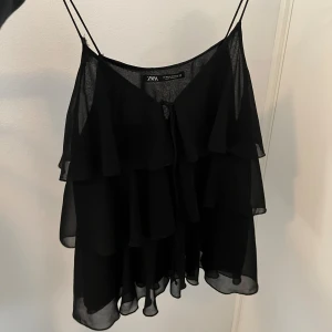 Svart volangig linnetopp från Zara - Ett snyggt volang linne ifrån zara, använt fåtal gånger och har en liten skavank på själva bandet men är i topp form utöver det, vill man ha en bild på så är de ba att skriva!🩷