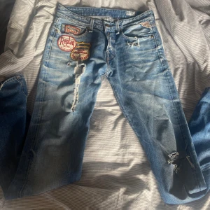 Replay jeans med patchar och slitningar - Snygga ljusblå Replay jeans med broderade patchar och slitningar på benen. Straight fit med låg midja. W 29 L 34