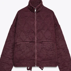 Quiltad vinröd jacka med dragkedja - Säljer en quiltad vinröd jacka med hög krage och hel dragkedja framtill. Jackan har två stora fickor, justerbar dragsko nertill. Overzised passform och långärmad modell, perfekt för kyligare dagar. 