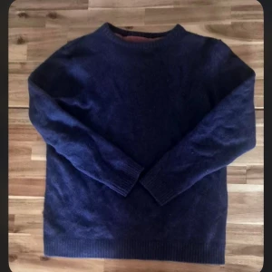 Mörkblå stickad tröja - En klassisk mörkblå stickad tröja med rund halsringning och långa ärmar. Perfekt för kyliga dagar och enkel att matcha med jeans eller chinos. Tröjan har ribbade muddar vid ärmslut och nederkant för en snygg passform. OBS (står L men passar Xs-S