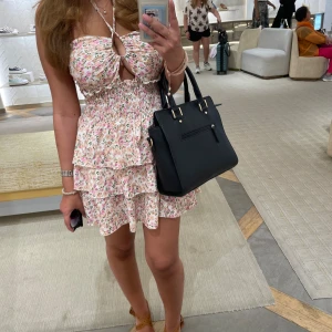 Blommig kort sommarklänning med volanger - Supersöt kort klänning med blommigt mönster! Köpt i Annecy, Frankrike💞 Säljer pga kommer inte till användning. Banden där framme kan man knyta hur man vill, man kan också ha den off shoulder💞 stretchig i materialet så passar nog xs-m!