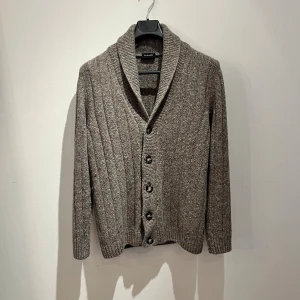 Brun ribbad kofta från Sand Copenhagen - Säljer en brunmelerad kofta från Sand Copenhagen med grov ribbstickning och bred krage. Koftan har fyra knappar framtill och långa ärmar. Perfekt för dig som gillar klassisk stil med en chill touch. Hör av er vid frågor