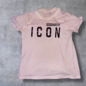  Dsquared2 ICON t-shirt - Snygg vit  t-shirt från Dsquared2 med svart 'ICON'-tryck på bröstet. Klassisk rund hals och korta ärmar. Perfekt för dig som vill sticka ut med en trendig och ikonisk look.