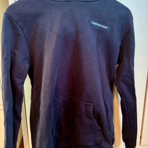 Mörkblå hoodie från Peak Performance - Snygg mörkblå hoodie från Peak Performance med broderad logga på bröstet. Tröjan har huva, känguruficka och är tillverkad i mjuk bomull. Perfekt för chill dagar eller när du vill ha en clean och sportig look.