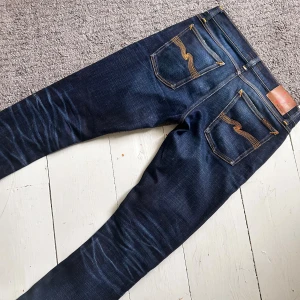 Mörkblåa Nudie  Long John Jeans - Sjukt snygga Nudie jeans med en grym fading. | W29 L32 | Nypris 1699kr | Som nya, riktigt bra skick. | Längd ca 100cm, midja ca 40cm. | Skriv vid minsta fundering, priset är ej hugget i sten!