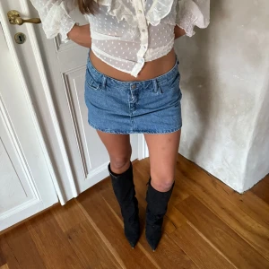 Blå jeanskjol i klassisk modell - Säljer en blå jeanskjol i klassisk, rak modell med normal passform. Kjolen är kort och har en enkel design med fickor och bälteshällor. Perfekt för dig som gillar en tidlös denimlook.