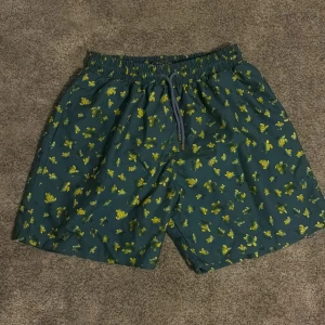 Vilebrequin badshorts med sköldpaddor - Snygga badshorts från Vilebrequin i marinblått med gult sköldpaddsmönster. Shortsen har elastisk midja med snörning och innerbyxa i mesh. Perfekta för stranden eller poolen, klassisk Vilebrequin-stil med coolt print.