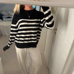 Svartvit randig stickad tröja - Mysig stickad tröja med svart och vita horisontella ränder. Tröjan har rund hals och långa ärmar med loose passform. Perfekt för dig som gillar klassisk stil med en chill vibe. Materialet är mjukt och känns skönt mot huden.