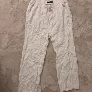 Vita linnebyxor från lager 157 - Säljer ett par vita linnebyxor från lager 157 i storlek M. Byxorna har elastisk midja med snörning, sidofickor och en bakficka. De är raka i modellen och har en avslappnad passform.