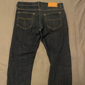 Mörkblå Tiger Of Sweden jeans - Snygga mörkblå Tiger of sweden jeans med klassisk femficksdesign och kontrastsömmar. Jeansen har rak passform och är tillverkade i slitstarkt denim med en skön känsla. Perfekta för dig som gillar stilrena och tidlösa jeans. W29 men passar W30, L32