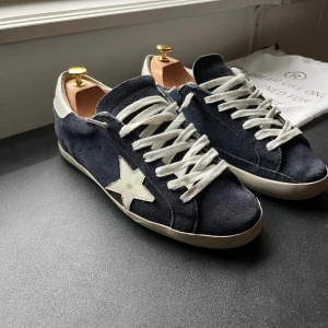 Golden goose superstar - Säljer dessa asfeta Golden goose som är i en perfekt mörkblå färg. Denna colourway är sjukt populär så missa inte dessa! Lite heel drag som syns på sista bilden men i övrigt inga defekter! Äkthetsbevis samt dustbag kommer med. Hör av er vid frågor eller funderingar!🤝