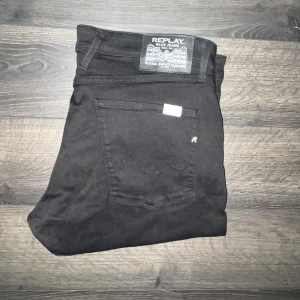 Replay Anbass jeans  - Svarta jeans från Replay med klassisk femficksdesign och diskret logga på bakfickan. Modellen har smal passform och raka ben, tillverkade i stretchigt bomullsmaterial för extra komfort. Perfekta för dig som gillar en stilren och enkel look. Midja 50cm, längd 102cm. JAG SKICKAR EJ FLER BILDER NÄR JAG BÄR JEANSEN! för storleksguide hänvisar jag till måtten och för bättre inblick i passformen rekommenderar jag att googla på modellnamnet :) s3