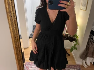 Svart kort klänning från Zara - Klänning från Zara med puffiga korta ärmar och v-ringad omlottfront. 