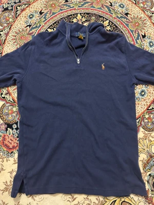 Marinblå half zip tröja Polo Ralph Lauren - Snygg marinblå långärmad tröja från Polo Ralph Lauren med half zip och klassisk broderad logga på bröstet. Tröjan har ståkrage och är gjord i mjuk bomull, perfekt för chill dagar. Passar dig som gillar stilren och enkel design. Pris kan diskuteras, storleken är S 