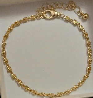 Tunn guldpläterad kedjearmband - Snyggt, elegant och tunt armband med tvinnad kedja i guldpläterad metall. Justerbar längd med flera öglor och en liten rund detalj vid låset. Perfekt för dig som gillar minimalistisk och stilren design.