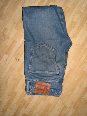 Levi's 512 blå jeans straight fit - Säljer ett par klassiska Levi's 512 jeans i ljusblå tvätt. Modellen har rak passform, fem fickor och hög midja. Jeansen är tillverkade i slitstarkt bomullsdenim och har den ikoniska Levi's-lappen bak samt röd Levi's-tag på bakfickan.
