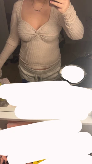 Beige ribbad omlottopp med lång ärm - Säljer en beige ribbad topp med omlottdetalj framtill och lång ärm. Toppen har en snygg v-ringning och är figurnära i modellen. Perfekt för dig som gillar neutrala färger och stilrena detaljer.