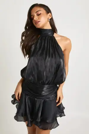 Supersnygg svart kort klänning från boohoo med   volangdetaljer som är helt oandvänd, prislapp sitter kvar. Klänningen har halterneck med knyt i nacken, öppen rygg och ett glansigt, flowy tyg som ger en lyxig känsla. Perfekt för jul och nyår, slutsåld i storleken på hemsidan! ✨🤩