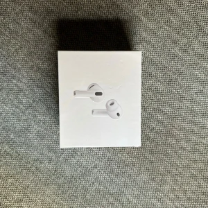 Apple AirPods Pro - Säljer ett par Apple AirPods Pro i oöppnad originalförpackning. Modeller A2083, A2084, A2190. Aktiv brusreducering, trådlös laddning och hög ljudkvalitet. Kartongen är förseglad och i mycket gott skick, endast mindre märken i plasten. Perfekt för dig som vill ha premium trådlösa hörlurar.