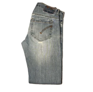 Dondup george ljusblå skinny jeans - Dondup george jeans i ljusblå tvätt med slitningar och trasiga detaljer vid knäna. Skinny fit med klassiska fem fickor och snygga broderade detaljer på bakfickorna. Tillverkade i Italien av mjukt jeanstyg med stretch för skön passform. Har även en defekt vid knät, kan gå bort i tvätten med lite medel.