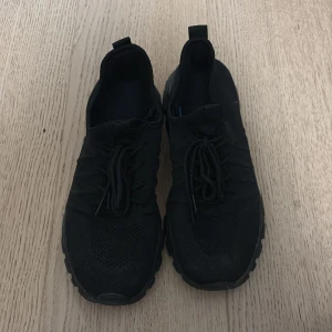 Svarta sneakers - Svarta sneakers med stickad ovandel och platt sula. Använda endast en gång pga fel storlek