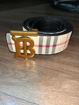  Burberry bälte med guldfärgat spänne - Säljer ett snyggt Burberry bälte som man kan ändra sida på så man kan ha svart eller beige