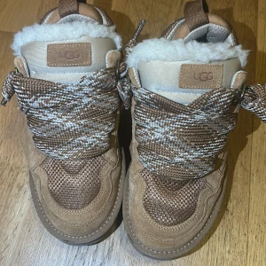 UGG sneakers med pälsfoder och snörning - Säljer mina UGG Lowmel sneakers i färgen beige, storlek 38. De är små i storlek – passar bäst för dig som vanligtvis har 37–37,5. Använda endast ett par gånger och fortfarande i mycket fint skick. Inga skador eller fläckar, bara små tecken på normalt bruk. Supersnygga och bekväma sneakers i klassisk UGG-stil.  Köpa i Januari 2025 men de passar inte mig och det därför de säljs, kvitto finns.