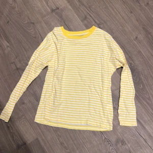 Gul och vit randig tröja Bik Bok XS - Säljer en fräsch gul och vit långärmad tröja från Bik Bok i storlek XS. Tröjan har ett klassiskt randigt mönster och rund halsringning med gul kant. Perfekt för dig som gillar färgglada och enkla plagg. Materialet är mjuk bomull som känns skönt mot huden.