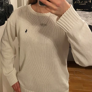 Ralph Lauren stickad tröja - Vit stickad tröja från Ralph Lauren med marinblå logga broderad på bröstet. Passar storlek XS-L, bror på hur man vill den ska sitta! 
