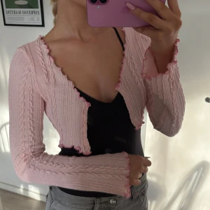 Ljusrosa croppad bolerotopp - Superfin ljusrosa y2k bolerotopp i stickat material med långärmad och croppad passform och har volangdetaljer längs kanterna! 💗