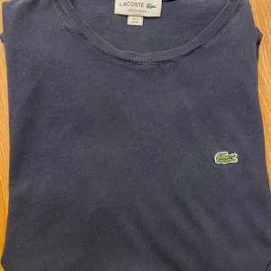 Marinblå Lacoste T-shirt - Marinblå T-shirt från Lacoste i jätte bra skick utan större användning.  Storlek M🏷️ Fraktas inom 24h✅ Kommer från päls- och rökfritt hem 🚭  Skriv vid fler frågor eller intresse 🌟