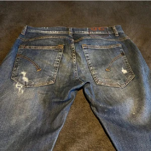 Dondup jeans med slitningar, blå - Säljer ett par Replay Grover jeans i blå tvätt med coola slitningar och distressed detaljer. Jeansen har klassisk femficksdesign, orange sömmar och raka ben. Materialet är robust denim som ger en schysst streetkänsla.